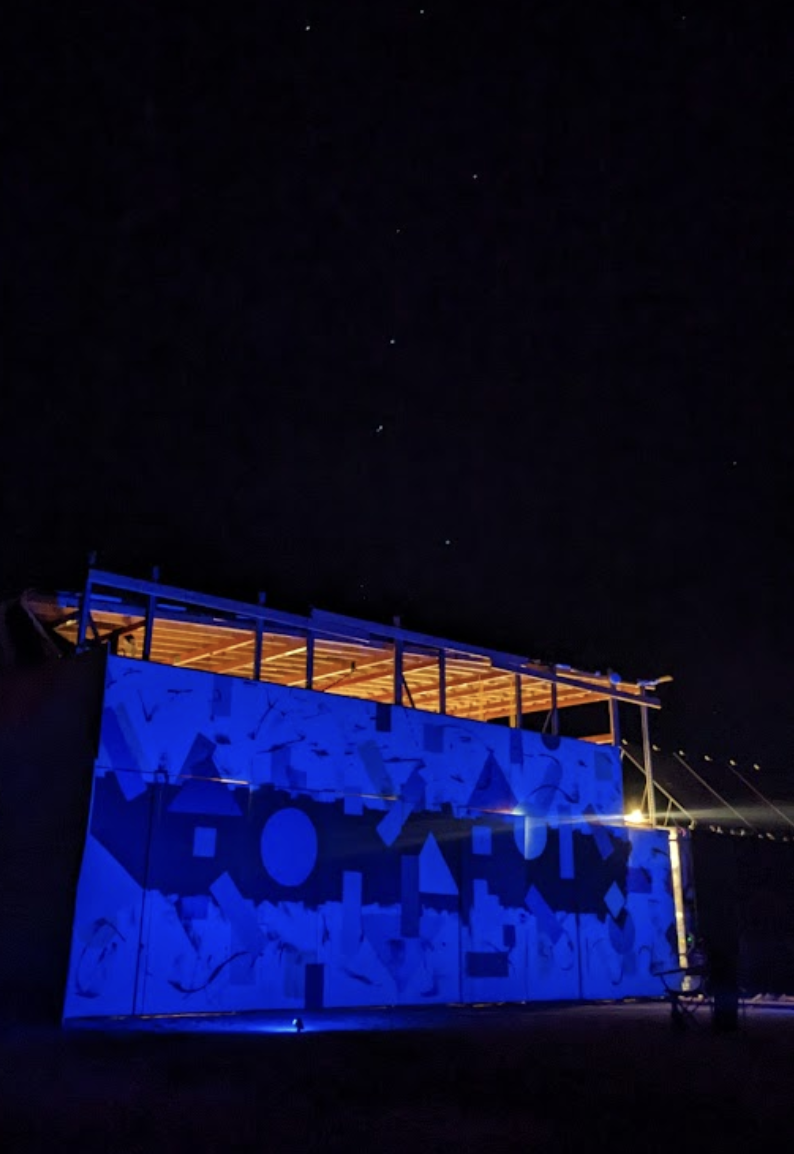 Structure lit blue against a starry desert night sky