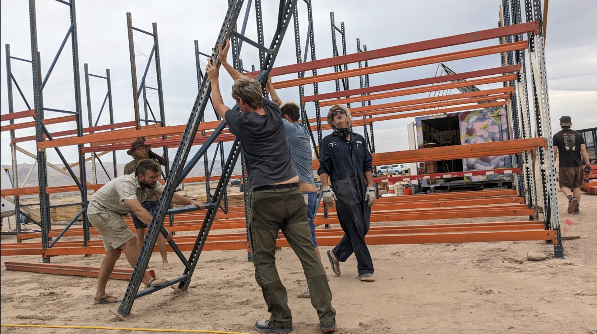 Residents raising pallet-rack framing to build the desert workshop